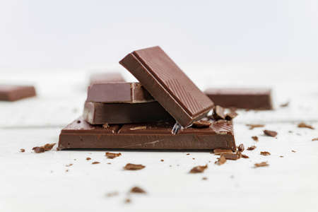 Chocolate bars on wooden table. Broken pieces of dark chocolate. Food backgroundの写真素材