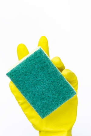 hand with yellow glove holding green sponge for cleaning on white backgroundの写真素材