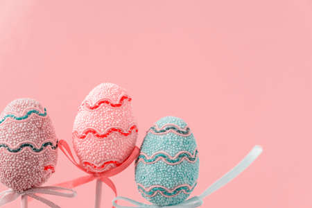 Easter colorful decorated eggs stand on a sticks on pink background. Minimal easter concept. Happy...