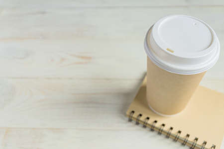 craft paper coffee cup and notebook diary with copy space on wooden background
