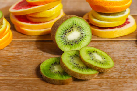pile of slices of oranges, lemons, kiwi, grapefruit on wooden background.