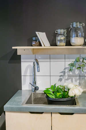 wash metal sink and various glass jars on metal table next to basket with flowers. Flowershop...