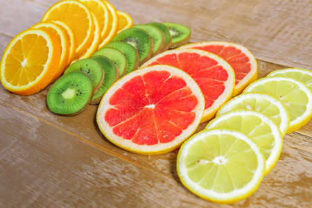 frame with slice of oranges, lemons, kiwi, grapefruit pattern on wooden background. copy space.の写真素材