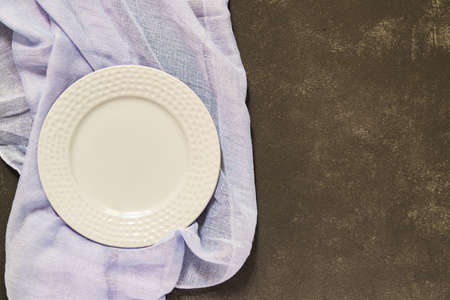 Top view of empty served plate, gray textile on black concrete background. Copy space.