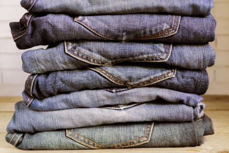 Stack of blue jeans on wooden shelf. Beauty and fashion clothing concept, toned
