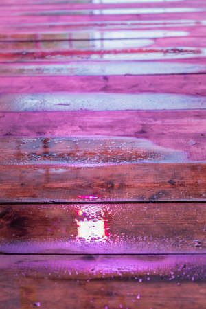 Wet wooden table under LED grow light. Background texture