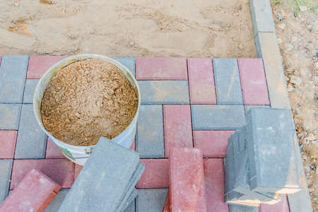 Worker laying red and gray concrete paving blocks. Road Paving, construction.の写真素材
