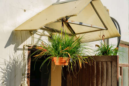 entrance to the old house with porch decorated with flowers in hanging pots.の写真素材
