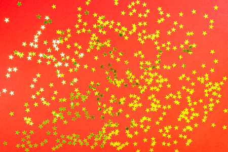 Red backdrop with glitter and golden stars confetti. Festive holiday bright background