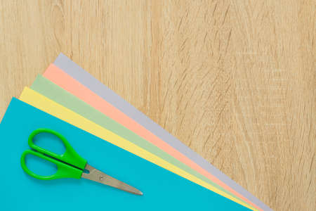 Top view of multicolored paper and scisors on wooden table. Top view. Arrangement for creative work or craft.の写真素材