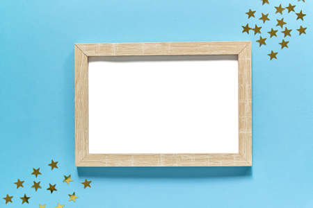 Photoframe with golden glitter confetti stars on blue background. Festive flat lay. Mock up for you...