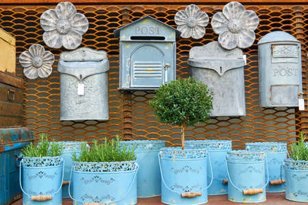 Flea market window shop with gardening decoration - vintage metal flowerpots with herbs and rusty postboxesの写真素材
