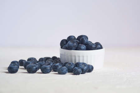 close up of bowl with blueberries on white concrete background