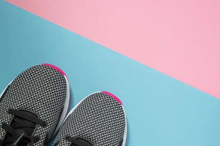 A pair of sport shoes on multiclored surface. New black and white woman sneakers on pink and blue pastel background with copy space. Top view, flat layの写真素材