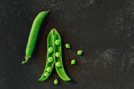 Vegetable backdrop vith copy space for your projects. Close up of fresh ripe green peas on black backgroundの写真素材