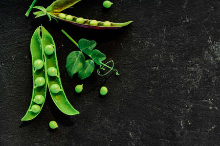 Vegetable backdrop vith copy space for your projects. Close up of fresh ripe green peas on black backgroundの写真素材