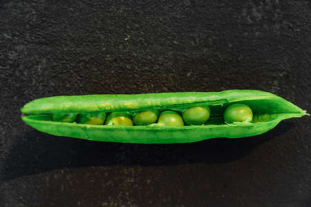 Vegetable backdrop vith copy space for your projects. Close up of fresh ripe green peas on black backgroundの写真素材