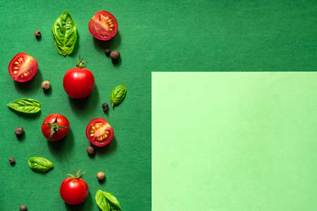 Halved Juicy Cherry Tomatoes and Basil Leaves on a green background. Concept for healthy nutrition. Top view. Copy space.の写真素材