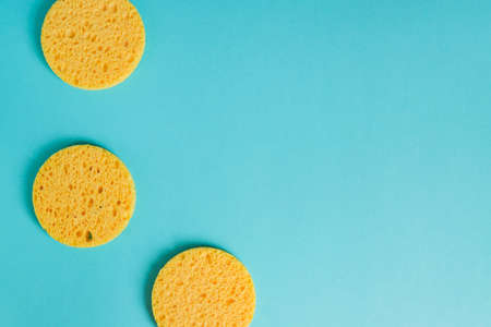 yellow round sponges on pastel blue background, Facial care. Cosmetic device. Deep skin cleansing.