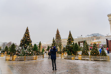 Moscow, Russia - December 20, 2018: Tourist take a picture of Christmas decorated Manezhnaya Square. Many christmas trees on Red Square backgroundのeditorial素材
