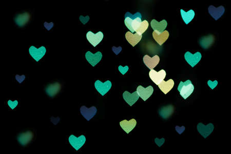 Multicolored hearts bokeh of blue color on black background. Texture for holidays