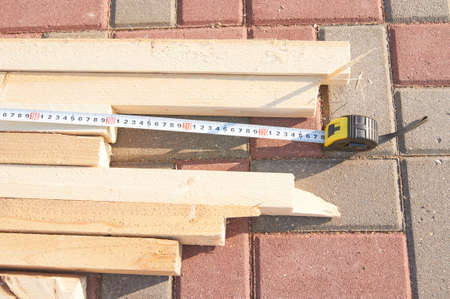 Worker measures wooden beams on the tile floor Construction works