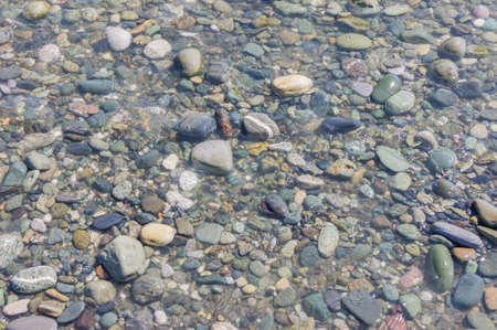 pebble coastline. Seashore with transparent water and small stones