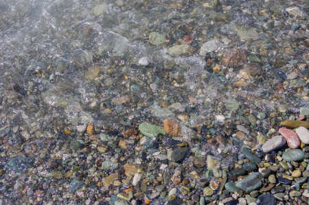 pebble coastline. Seashore with transparent water and small stones