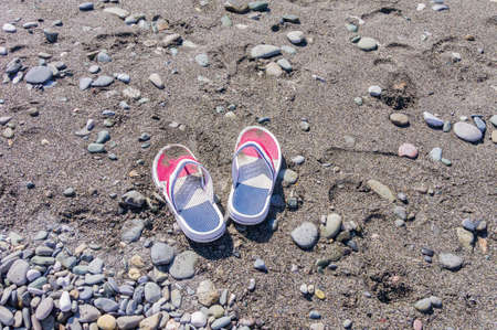 Children's flip flops on the beach. Copy space. Tourism and vacation conceptの写真素材