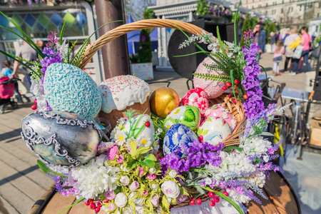 Easter street vestival in Moscow, Russia. Wicker basket full of painted easter eeggs, cake and flowers.の写真素材