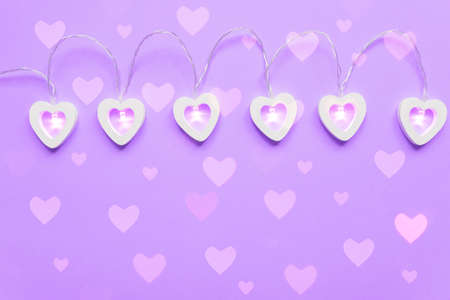 Wooden eart-shaped harland on purple background. Greeting card for st valentine's day, Copy space
