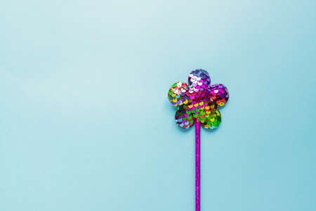 magic stick from sequins in flower shape on pastel blue background. Creative flat lay in minimal styleの写真素材