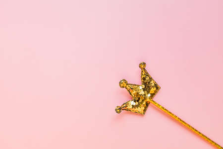 golden magic stick from sequins in crown shape on pastel pink backgeound. Creative flat lay in minimal styleの写真素材