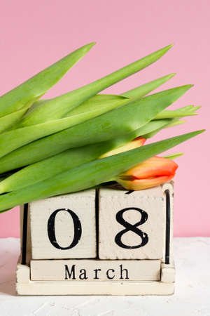 Intarnational women day. Wooden calendar 8 of march and red tulips on pink background
