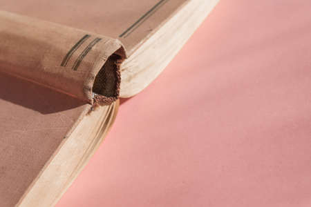 Open hardcover old book on pink background with copy space. Educational concept