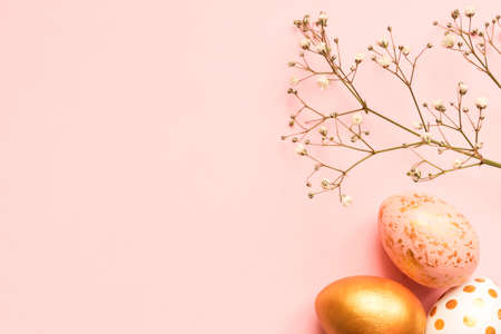 Top view of wooden painted eggs in gold, black and rose colors with branch of gypsophila on pink background. Happy easter background with copy spaceの写真素材