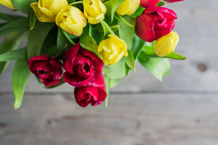 Top view of bouquet of red and yelow tulips. Floral background. Festive greeting card for mothers day or birthday. Copy space for text.の写真素材