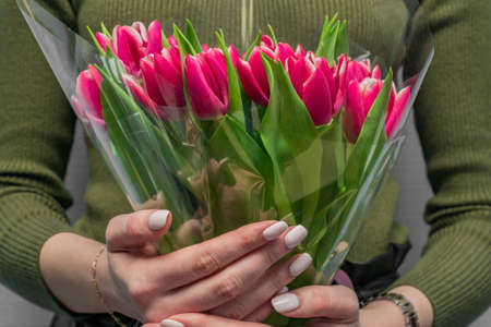 caucasian woman in green blouse holding bouquet of pink tulips. Gift for holidays.の写真素材