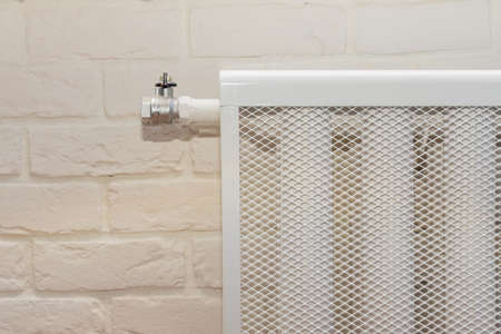 radiator heating device against a white brick wall. cozy house with modern interior room close upの写真素材