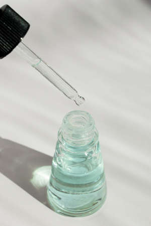 Dropper of essential oil, aromatherapy essence, or medicinal liquid on white backgroundの写真素材