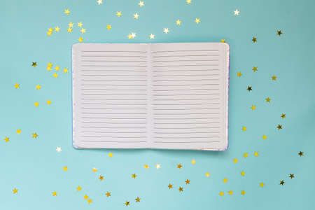 Open blank Notepad or planning on a blue festive background with shining stars. Creative layout for...