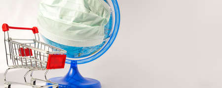 Coronavirus outbreak. World pandemia. Globe in medicine mask and shopping trolley on white...