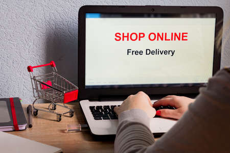 Shop online on Laptop Screen. Free delivery. E-commerce concept. Caucasian woman shop online from her homeの写真素材