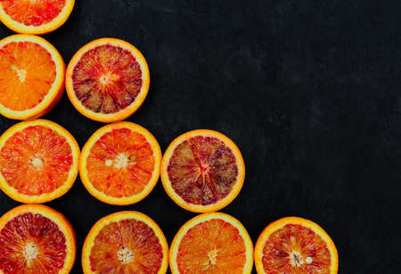 Organic Raw Red Blood Oranges in a rows on a black background. Copy space for text
