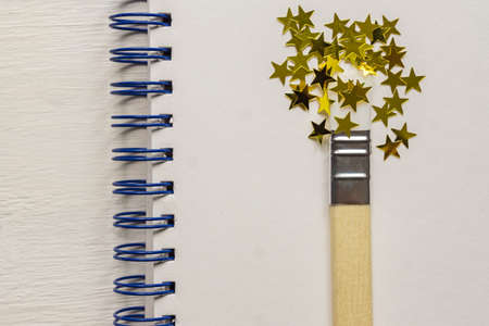 surreal paint brush drawing golden stars confetti. Artistic concept on sketchbook background.