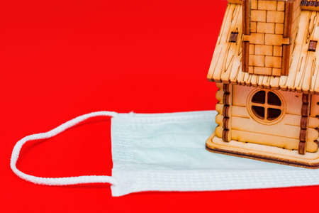Stay home. Self quarantine. Wooden house on medicine mask. Coronavirus prevention conceptの写真素材