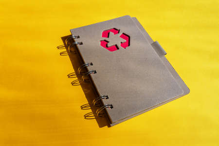 Planner of notebook with recycling sign on a cover on orange background. Consept of waste recyclingの写真素材