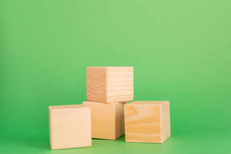 Construction of wooden cubes on green background with copy space. Mockup composition for design.の写真素材