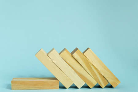 Wooden blocks on blue background. domino effect in business concept
