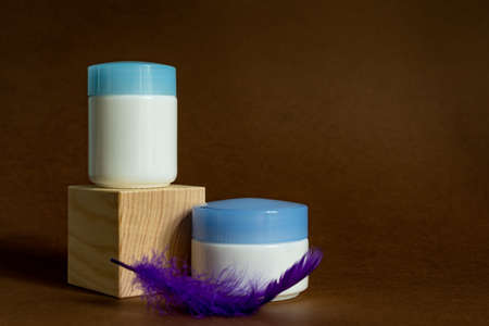 Display wooden podium with crem jars on a brown background. Face care containers. Cosmetics mockup....